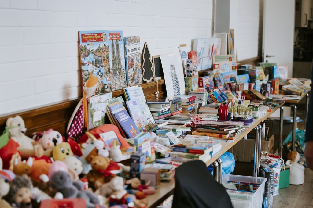 Reichlich bestückter Flohmarktstand mit Büchern, Kuscheltieren und Spielzeug